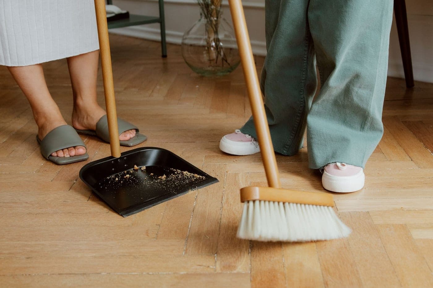Balai et pelle sur un parquet après le ménage